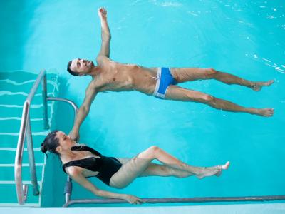 Zwei Personen im Pool, eine treibt und die andere entspannt sich.