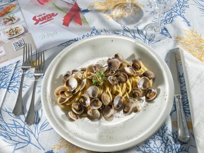 Teller mit Spaghetti und Muscheln auf dekorierter Tischdecke.