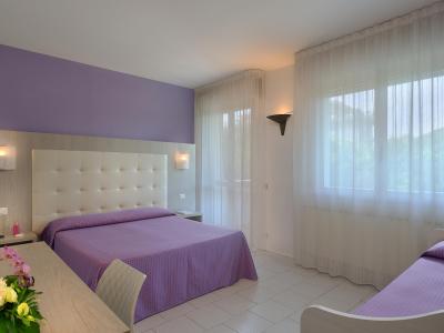 Camera moderna con letto matrimoniale e singolo, decorata in tonalità viola.