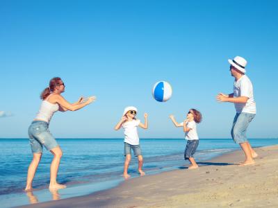 Family playing with a ball on the beach on a sunny day.