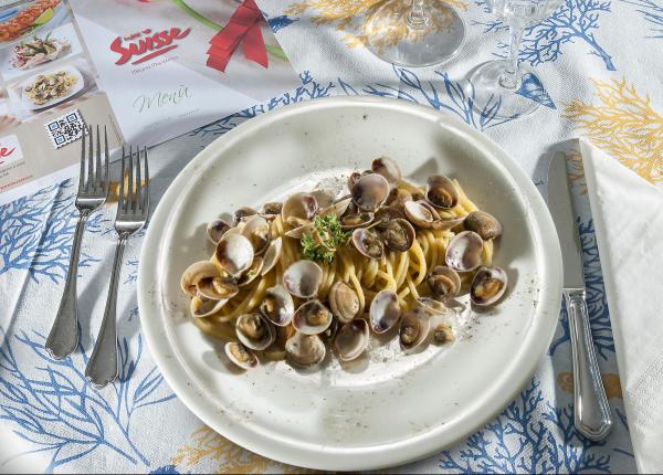 Teller mit Spaghetti und Muscheln auf dekorierter Tischdecke.