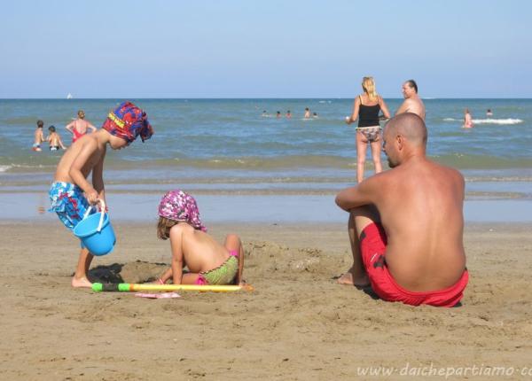 Famiglia gioca sulla spiaggia in una giornata di sole.