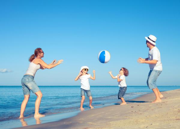 Family playing with a ball on the beach on a sunny day.