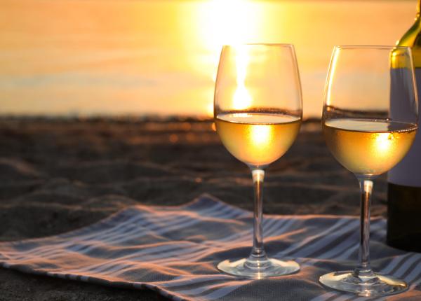 Due bicchieri di vino bianco al tramonto sulla spiaggia.
